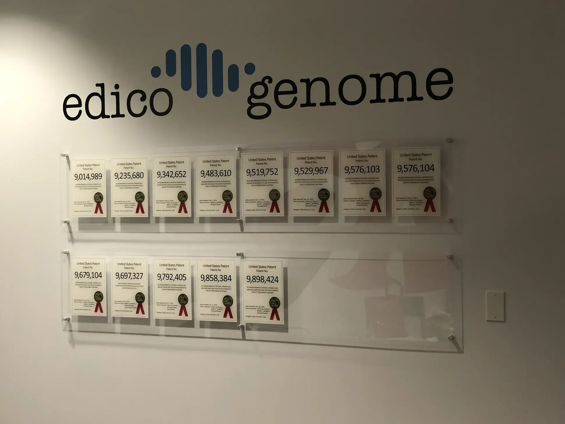 Custom wall signage displaying the Edico Genome logo and framed patent certificates in a life sciences facility