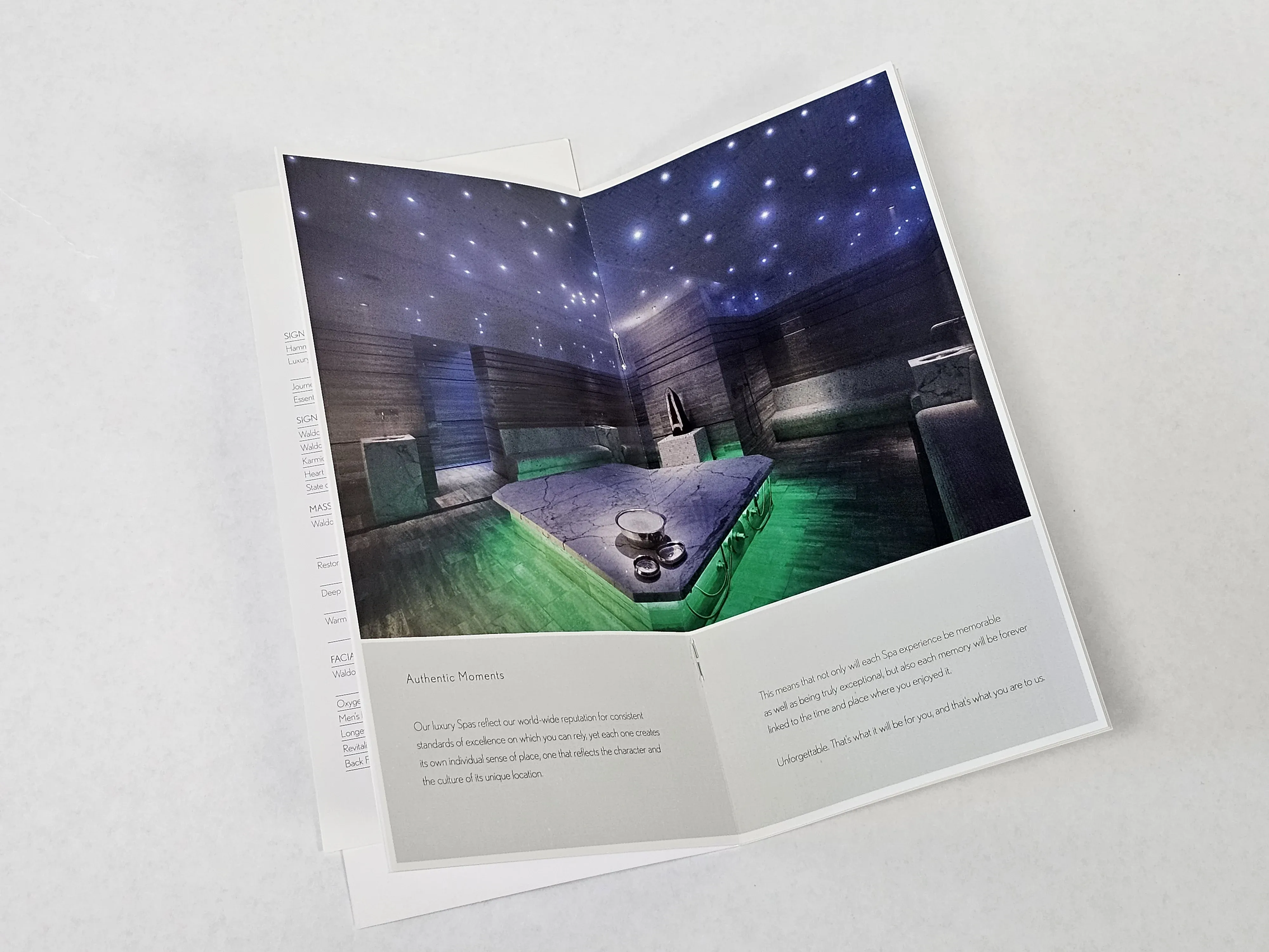 Open saddle-stitched brochure featuring a luxury spa interior photo with starry ceiling lights and green ambient lighting, alongside descriptive text about the spa experience.