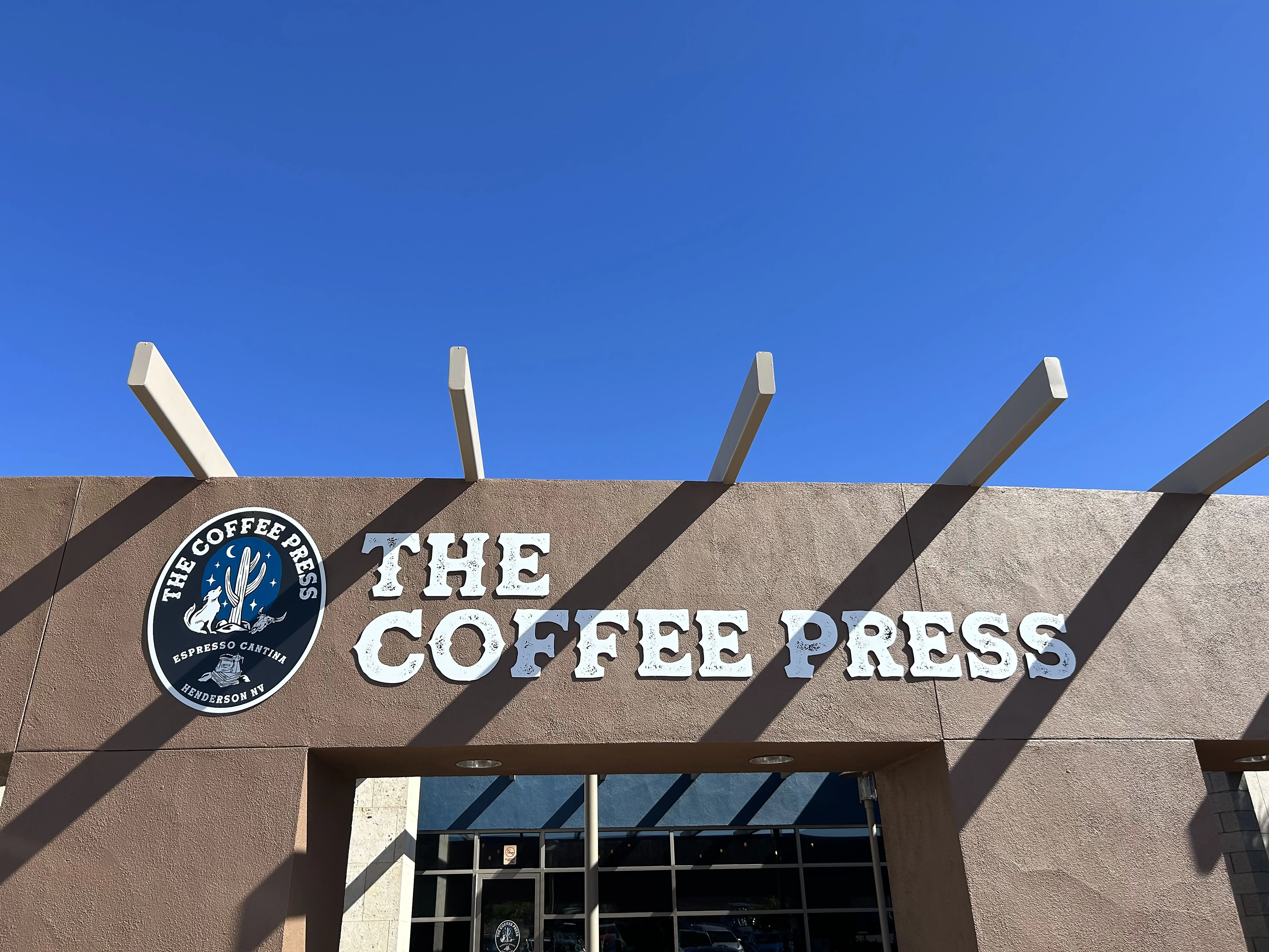 Exterior building sign with white graphics and logo for The Coffee Press café.