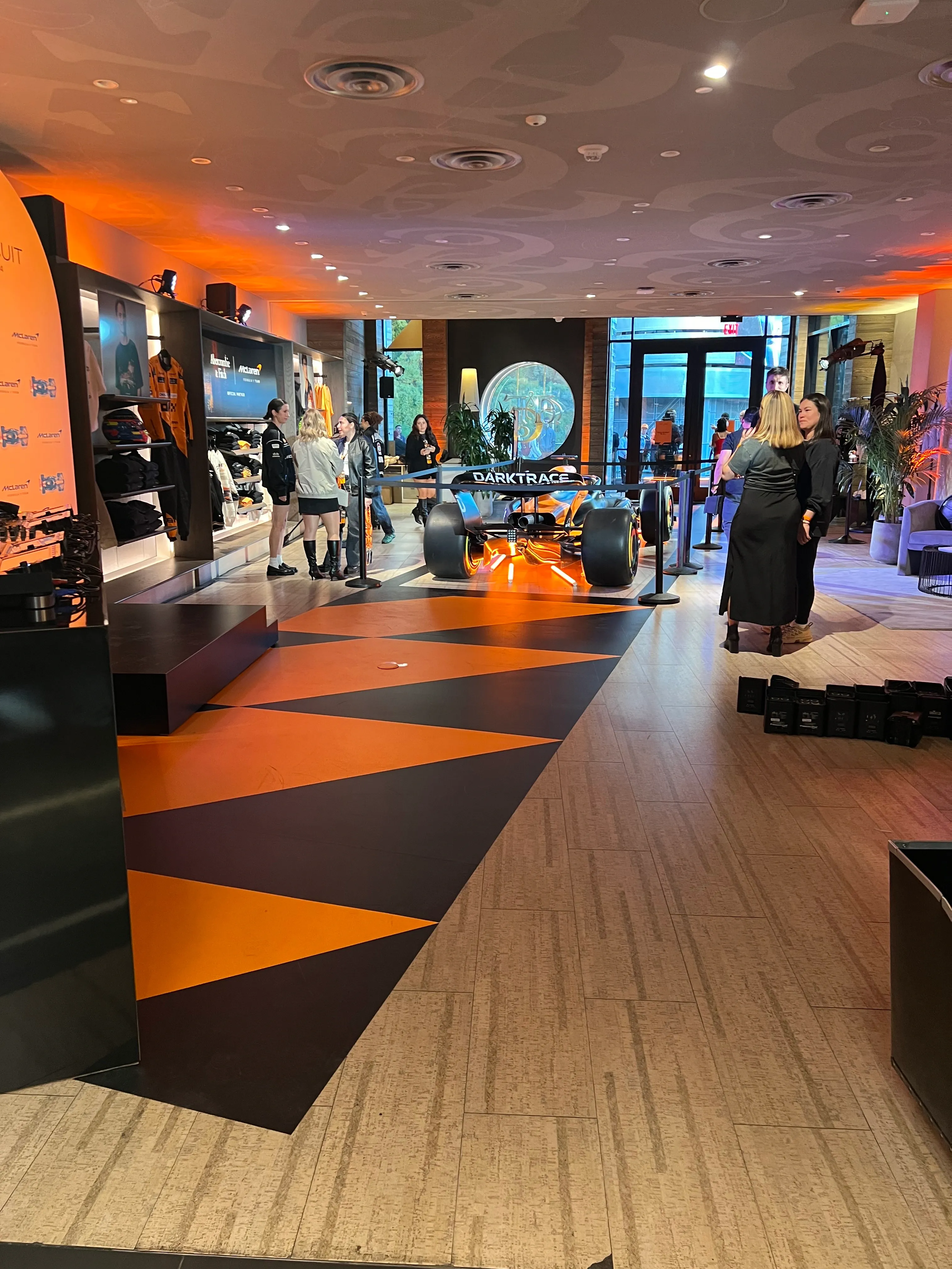 Bold orange and black directional floor graphics at a Las Vegas F1-themed retail event, guiding foot traffic and enhancing brand ambiance.